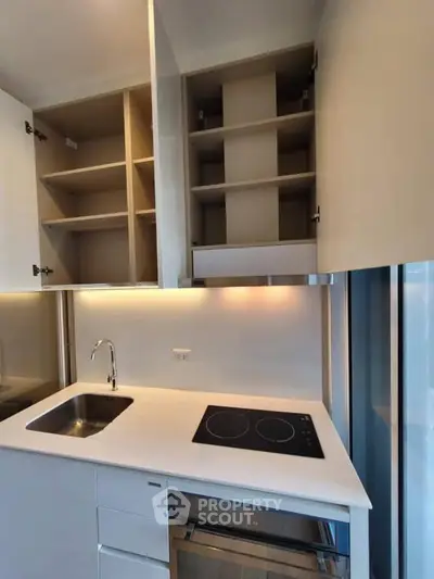 Modern kitchen with sleek cabinetry and electric cooktop in a stylish apartment.