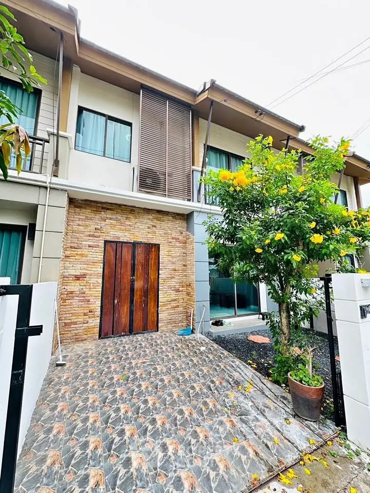 Charming two-story townhouse with stone facade and lush garden, perfect for modern living.