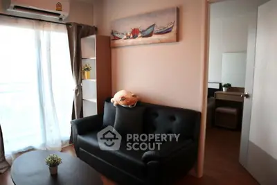 Cozy living room with black sofa and natural light, perfect for relaxation.