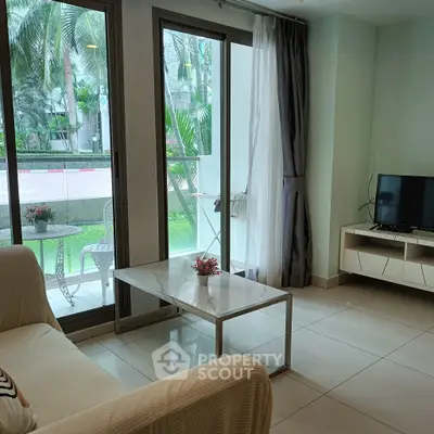 Modern living room with large windows and garden view, featuring a cozy sofa and sleek TV setup.