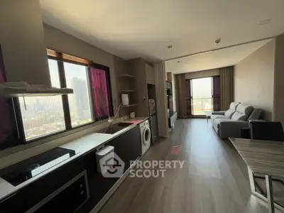 Modern open-layout living room with kitchen and city view, featuring sleek furniture and appliances.
