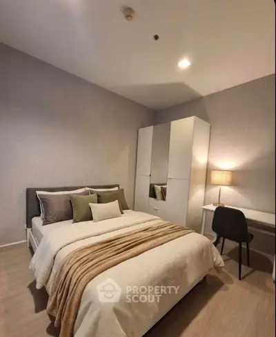 Cozy bedroom with modern decor, featuring a comfortable bed, stylish wardrobe, and a sleek desk with chair.