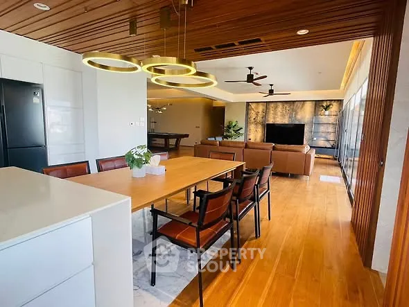 Modern open-plan living and dining area with stylish lighting and wooden accents.