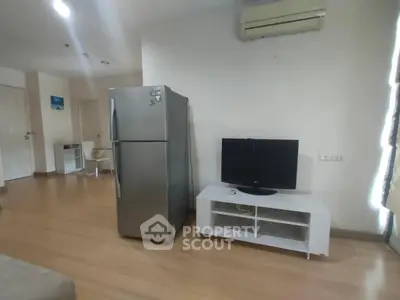 Modern living room with fridge, TV, and air conditioning in a cozy apartment.