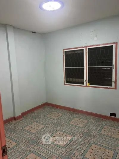Spacious empty room with tiled floor and barred windows, ideal for customization.
