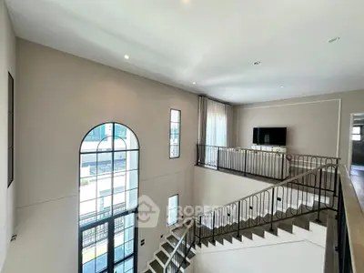 Elegant two-story living room with large windows and modern staircase
