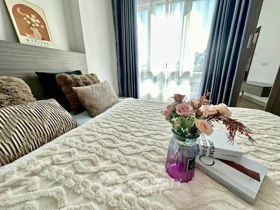 Cozy bedroom with elegant decor, plush pillows, and a vase of fresh flowers on a textured bedspread.