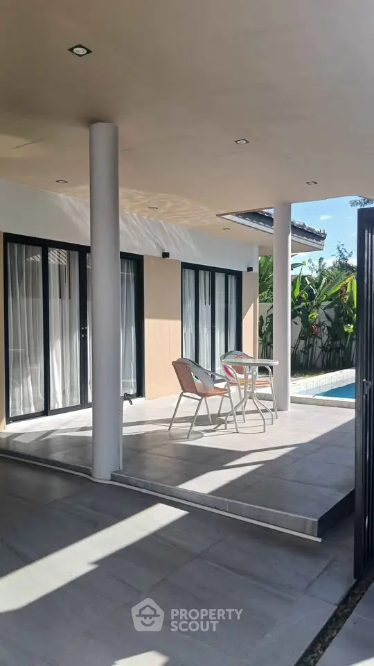 Charming patio with poolside view and modern outdoor seating in a serene setting.