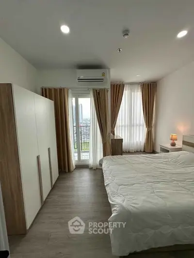 Modern bedroom with large window and balcony access, featuring sleek furniture and cozy lighting.