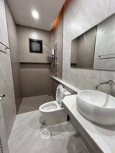 Modern bathroom with sleek design, featuring a wall-mounted sink, toilet, and shower area with elegant tiles.