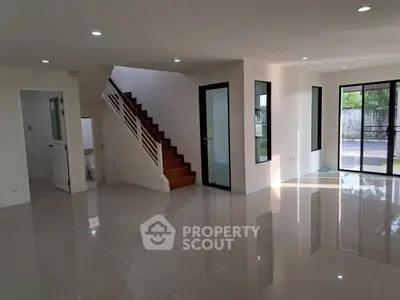 Spacious modern living room with glossy tile flooring and staircase
