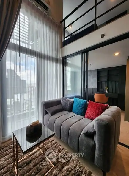 Modern living room with loft, large windows, and stylish decor in urban apartment.