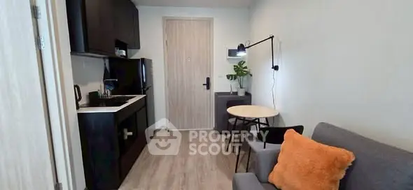 Modern compact living room with kitchenette, stylish decor, and cozy seating in a contemporary apartment.