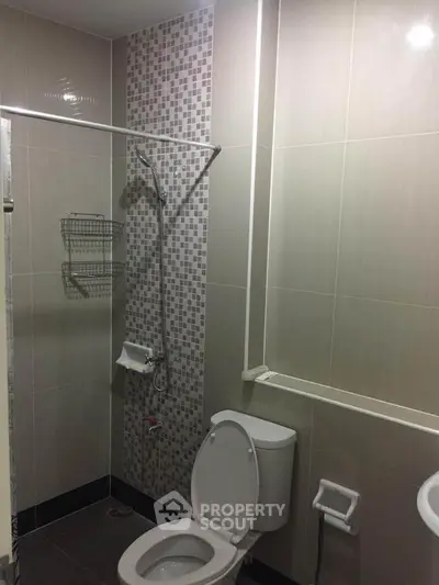 Modern bathroom with tiled walls and shower in a real estate property.