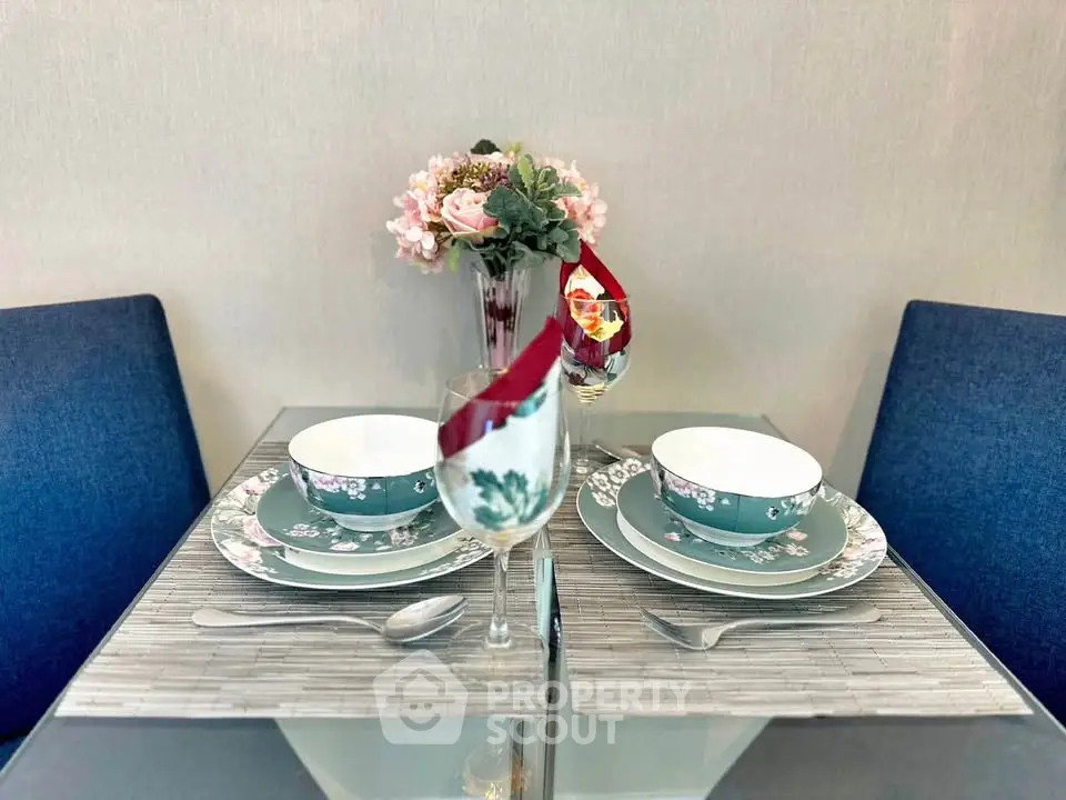 Elegant dining setup with floral dinnerware and blue chairs in a cozy dining area.