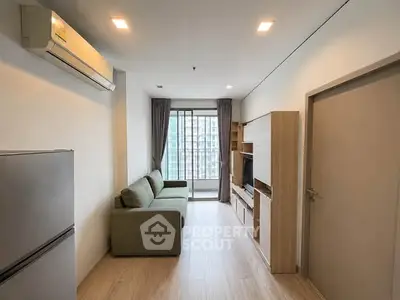 Modern living room with sleek furniture and large window offering city view.