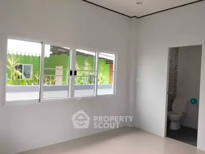 Bright room with large window and partial bathroom view, showcasing modern minimalist design.