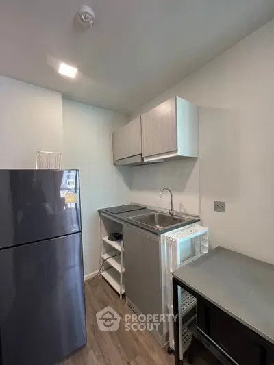 Modern compact kitchen with sleek cabinets and stainless steel appliances in a cozy apartment.