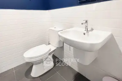 Modern bathroom with sleek white fixtures and stylish blue accent wall.