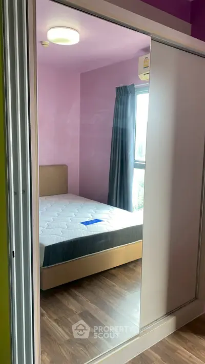 Modern bedroom with mirrored wardrobe and large window for natural light.