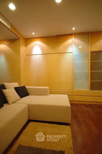 Modern living room with beige sectional sofa and wooden paneling