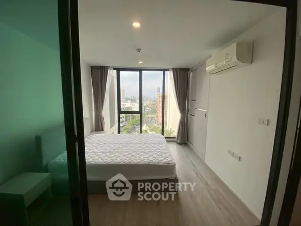 Modern bedroom with large windows and city view, featuring air conditioning and minimalist design.