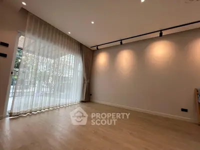 Spacious empty living room with wooden flooring and large window