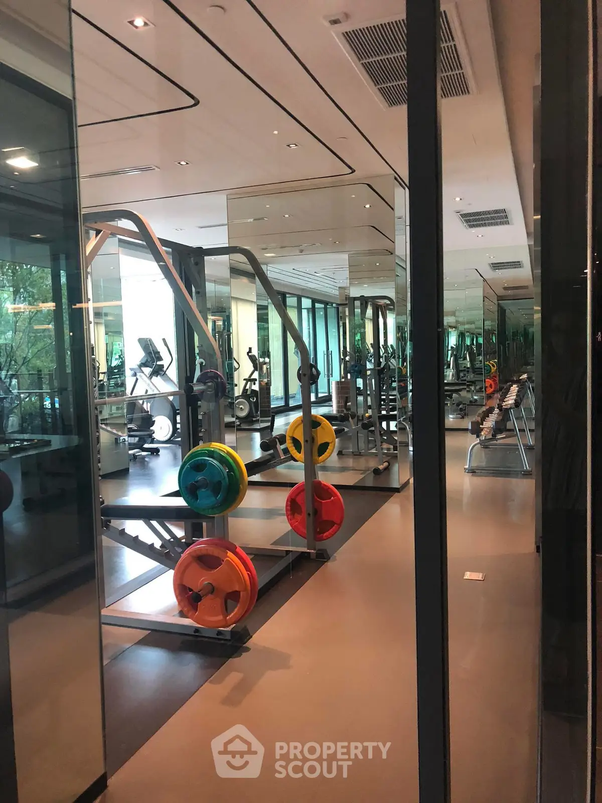 Modern gym with state-of-the-art fitness equipment and mirrored walls in luxury real estate.
