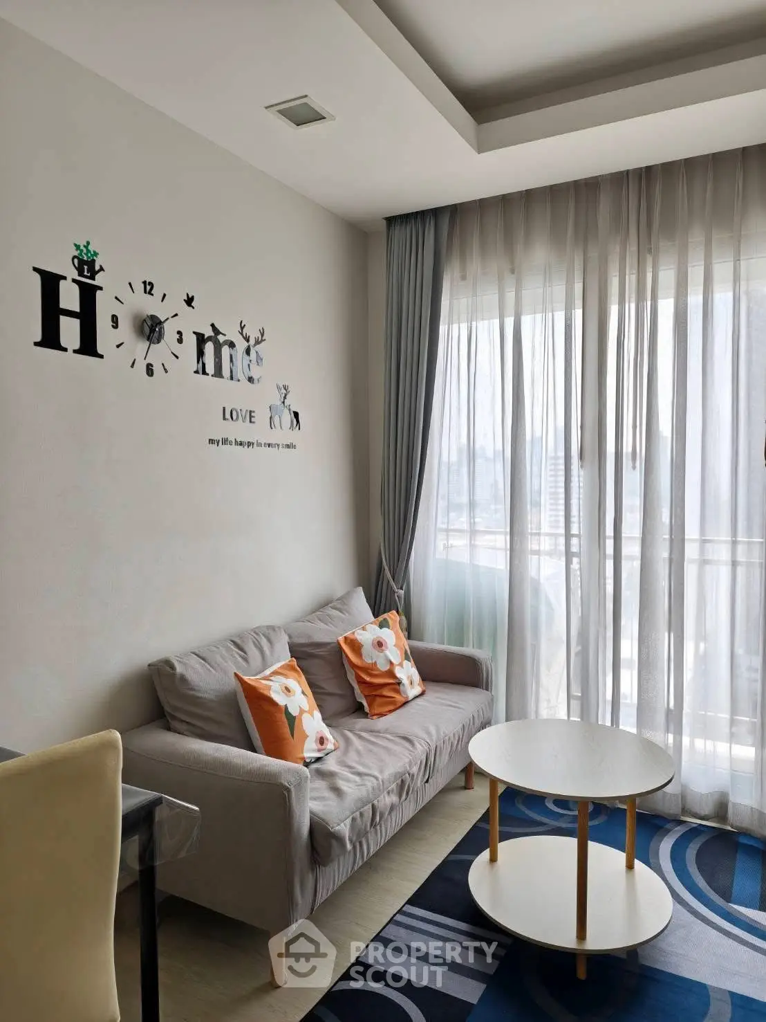 Cozy living room with stylish decor and natural light through sheer curtains.