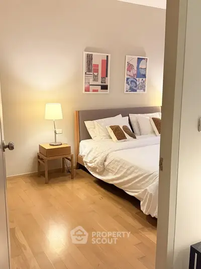 Cozy bedroom with modern decor and warm lighting, featuring a comfortable bed and stylish artwork.
