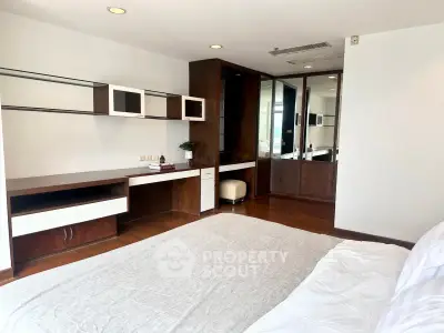 Spacious bedroom with modern built-in desk and wardrobe, featuring elegant wood finishes and ample natural light.