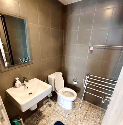 Modern bathroom with sleek fixtures and tiled walls, featuring a toilet, sink, and towel rack.