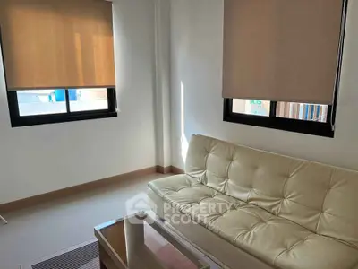 Cozy living room with modern sofa and natural light through large windows.