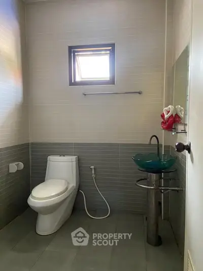 Modern bathroom with sleek design and unique glass sink, perfect for contemporary living.