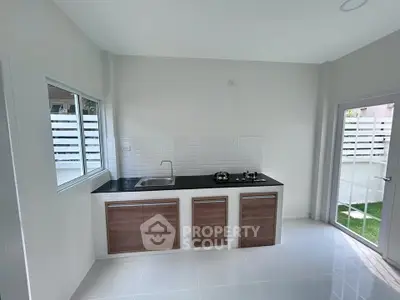 Modern kitchen with sleek design and ample natural light, featuring a gas stove and minimalist cabinetry.