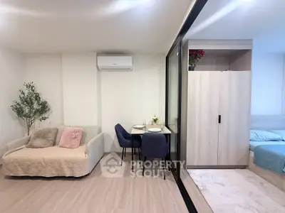 Modern living room with cozy sofa, dining area, and view into bedroom