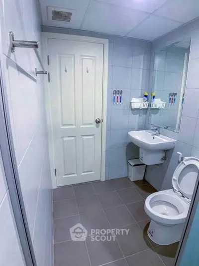 Modern bathroom with sleek design, featuring a wall-mounted sink and a large mirror.