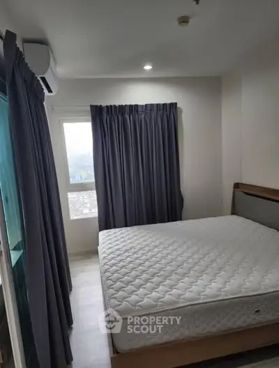 Cozy bedroom with large window and modern furnishings, perfect for relaxation.