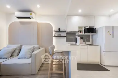 Modern open-layout living room and kitchen with sleek white cabinetry and cozy seating area.