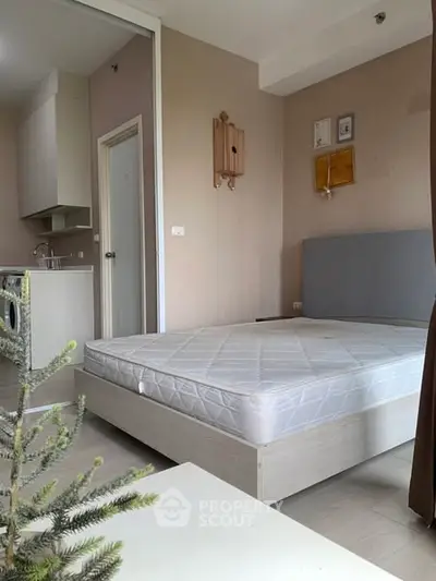 Cozy bedroom with modern kitchen and washing machine, ideal for urban living.