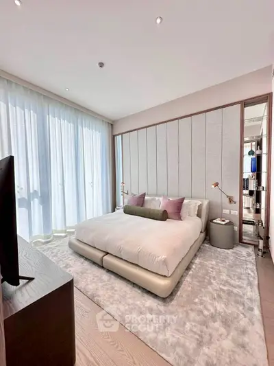 Luxurious bedroom with modern decor and large windows offering natural light.