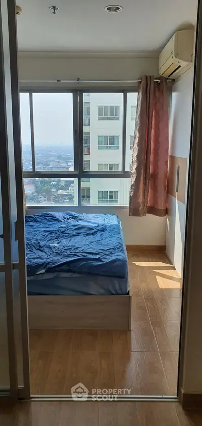 Bright bedroom with large window offering stunning city view in modern apartment.