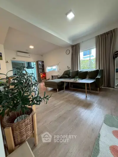 Spacious living room with modern decor and large windows, perfect for relaxation and entertaining.