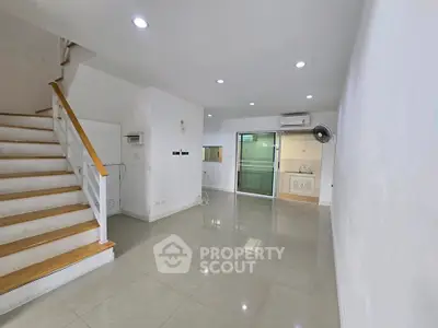 Spacious modern living room with staircase and open kitchen layout, perfect for family gatherings.