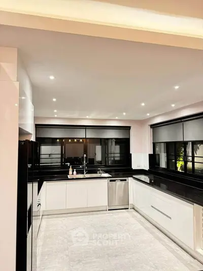 Modern kitchen with sleek black countertops and stainless steel appliances in a spacious open layout.
