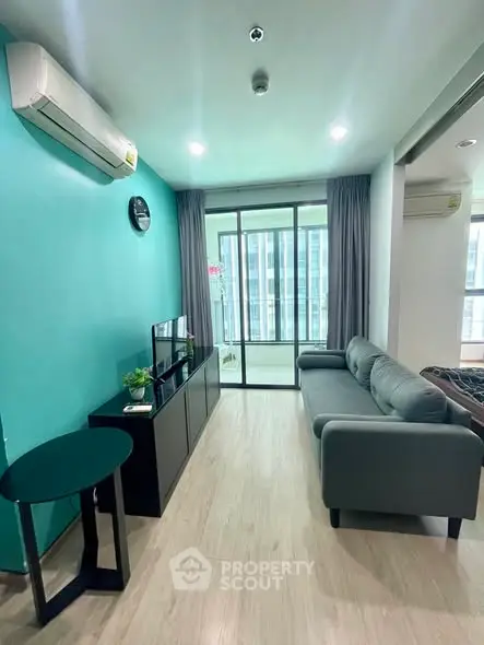 Modern living room with teal accent wall, sleek furniture, and balcony access in a stylish apartment.