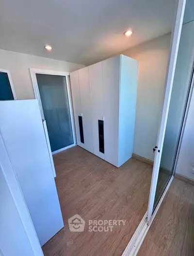 Modern storage room with sleek white cabinets and wooden flooring