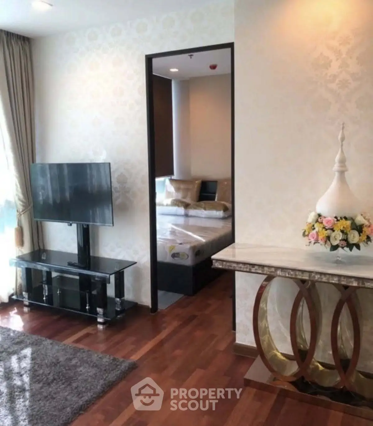 Elegant living room with hardwood floors and modern decor leading to a cozy bedroom.