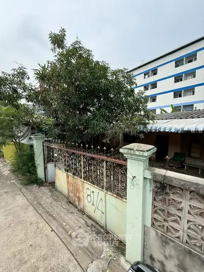 Charming fixer-upper property with potential, featuring a gated entrance and lush greenery, ideal for renovation.