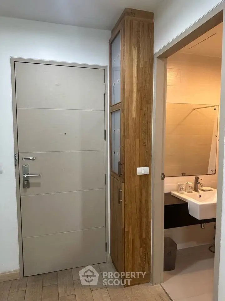 Modern apartment entrance with wooden cabinetry and bathroom view